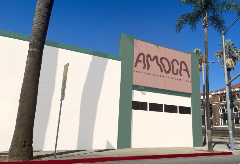 a white building front that had green trim with red paneling that says AMOCA